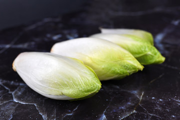 Pieces of raw Belgian endive leaf vegetables on dark background