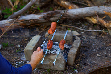 Sausages are grilled on skewers on hot coals, tasty street food sold at a meat barbecue, camping, picnic. Barbecue in the garden.