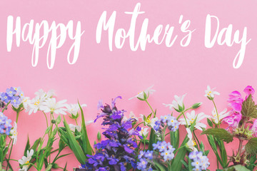 Happy Mother's day text, greeting card. Colorful spring flowers border on pink background flat lay...