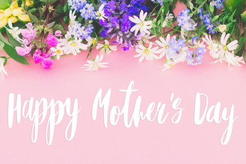 Happy Mother's day text, greeting card. Colorful spring flowers border on pink background with greeting sign. Floral greeting card. Happy Mothers day concept