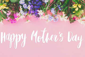Happy Mother's day text on colorful spring flowers bouquet on pink background. Floral greeting card. Happy Mothers day concept.