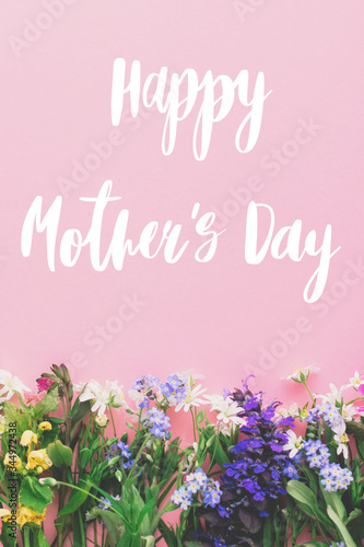 Happy Mother's day text, greeting card. Colorful spring flowers border on pink background flat lay with greeting sign. Floral greeting card. Happy Mothers day concept