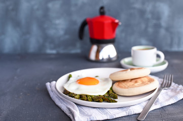 Healthy breakfast. Fried eggs, asparagus, bread and aromatic coffee on a gray background. Free place for text. Soft focus. Vertical