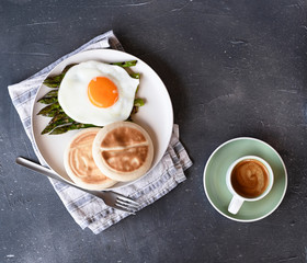 Healthy breakfast. Fried eggs, asparagus, bread and aromatic coffee on a gray background. Free place for text. Soft focus. Vertical
