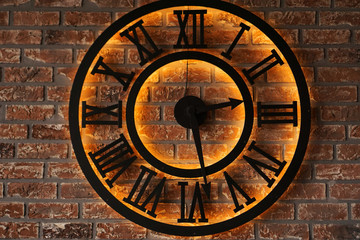 Close up old vintage retro style metal wall clock over background of grunge brick wall - loft style