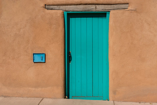 Turquoise Blue Wooden Door with Wood Beam Inset into Southwest Style Adobe Earthen Wall Building