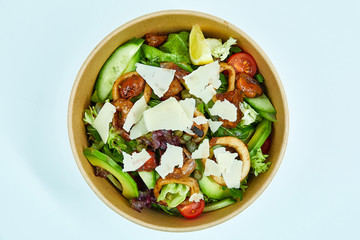 Seafood salad with grilled shrimps, mussels, squid rings, lettuce, cherry tomatoes, Parmesan cheese, capers, avocado and a slice of lemon in an artichoke box