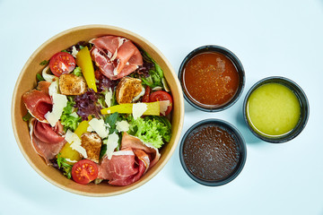 Salad with jamon, parmesan and feta cheese, cherry tomatoes, pear, lettuce, sun-dried tomatoes in a cardboard box