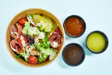 Salad with jamon, parmesan and feta cheese, cherry tomatoes, pear, lettuce, sun-dried tomatoes in a cardboard box