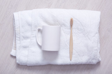 Obraz na płótnie Canvas Styled bathroom counter with soft towel, cup and toothbrush. White towel on light background, white cup, tooth brushing, clean, cleanse mouth, dental problems, morning procedures in bathroom.