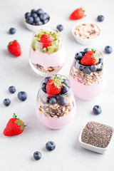 Chia seeds pudding with granola, blueberry and strawberry in glasses. Yogurt with chia seeds, berries, kiwi and muesli for healthy breakfast, copy space