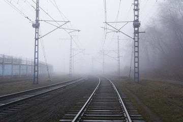 railroad rails lurking in fog in perspective