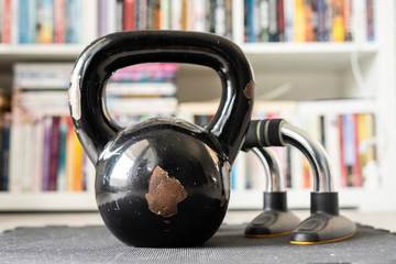 Naklejka na ściany i meble Close up on black kettlebell girya training weight and push up bars on the floor at home in day training equipment