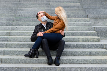 Young couple in masks on city street.