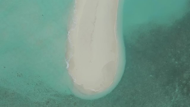 Small Tropical Island, Maldives small Island. Aerial view of crystal clear sea and white sand beach. Top view ocean waves slow motion 