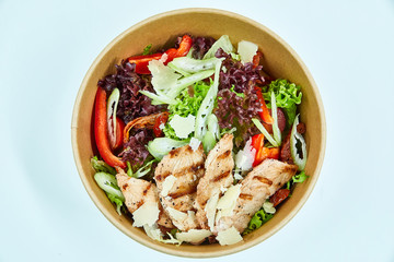 Salad with grilled chicken, parmesan cheese, cherry tomatoes, sun-dried tomatoes, lettuce, red pepper, celery in a cardboard box