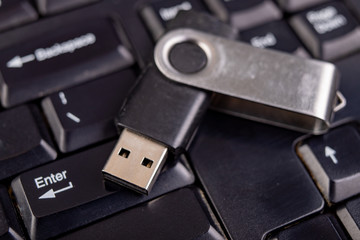 Black flash drive on a PC keyboard. Cache used to store temporary data.