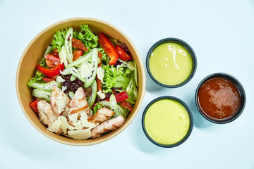Salad with grilled chicken, parmesan cheese, cherry tomatoes, sun-dried tomatoes, lettuce, red pepper, celery in a cardboard box