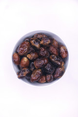 Semi dried date fruit in white bowl close up top view