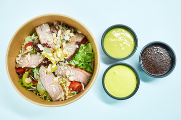Salad with grilled duck and cherry tomatoes, pear, lettuce, arugula, almonds in a cardboard box