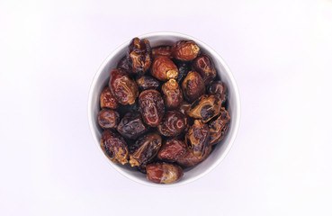 Pitted dates isolated in white bowl top view