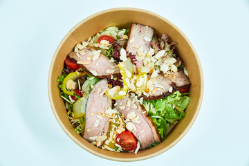 Salad with grilled duck and cherry tomatoes, pear, lettuce, arugula, almonds in a cardboard box