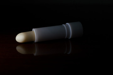 cocoa butter lipstick gloss, to moisturize chapped lips, on cold winter days. Concept photo with dramatic light, copy text space and black background