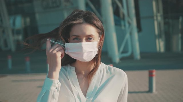 Pandemic is over. End of quarantine 2020. Relieved young european woman taking off surgical mask breath fresh air smile with much joy at camera. Outdoor portrait.