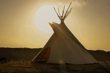 tipi lakota con el sol brillando en un atardecer