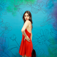 Dark-haired female model posing in red dress on flower background