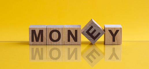 MONEY - word from wooden blocks with letters, sorry concept, yellow background.