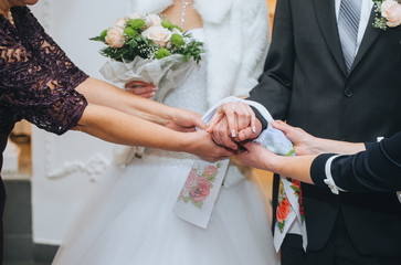 Parents hold the hands of the newlyweds, tied with a towel, a rushnyk in a knot at the wedding...