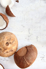 A broken coconut on a light textured background. Copy of the space.
