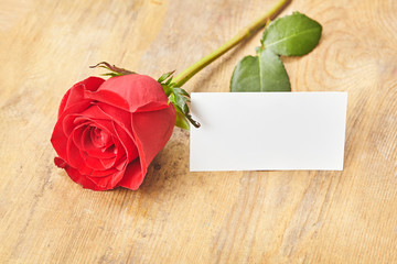 Blank card with red rose on a wooden background Close up