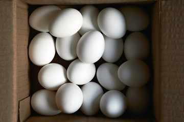 White eggs of oval shape in a brown box in the daytime on the top view. The concept of agricultural production