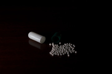 open white and green medicine capsule, showing the small particles that exist inside each capsule,...