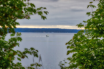 A Washington State Ferry crosses Puget Sound in the Pacific Northwest as seen through the trees on...