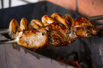 Shashlik or shashlyk cooked on metal skewers over charcoal. Grilled chicken wings, pork ribs, steaks with bones,  on metal skewers. Mix of several types of meat is roasted on fire at outside kitchen.