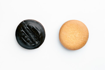 Round biscuit shortbread and one piece covered in chocolate on a white horizontal background in the top view. The concept of making homemade pastry and dessert