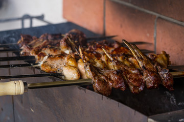 Shashlik or shashlyk cooked on metal skewers over charcoal. Grilled chicken wings, pork ribs, steaks with bones,  on metal skewers. Mix of several types of meat is roasted on fire at outside kitchen.