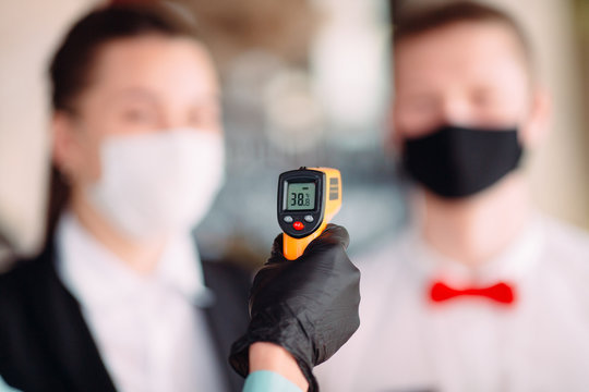 The Manager of a restaurant or hotel checks the body temperature of the staff with a thermal imaging device.