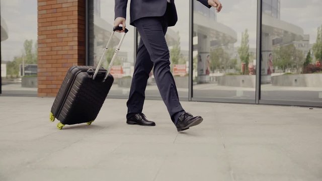 Young businessman with suitcase walking