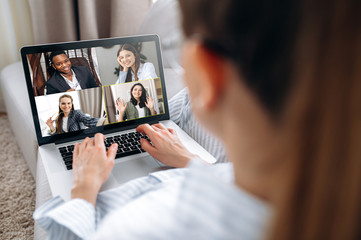 Business team working from home in a video conference. The back view of a girl who communicates...