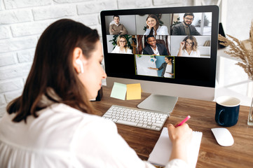 Online training. The back view of a girl who learns online by video conference online. On the...