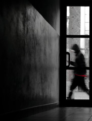 silhouette of a man in black and red walking down the street seen from behind the door