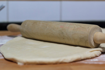 Raw dough and rolling pin on wooden board