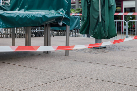 Selected focus at Red and white caution tape restrict outdoor eating area of cafe and restaurant which closed during epidemic of COVID-19 virus. COVID-19 restrictions on restaurant business in Europe.