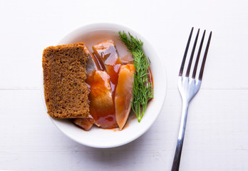 Herring in tomato sauce in a plate, brown bread and dill, fork