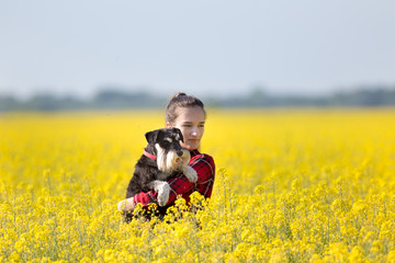 Girl holding dog in yellow rapeseed