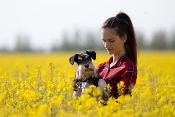 Naklejka na ściany i meble Girl holding dog in yellow rapeseed